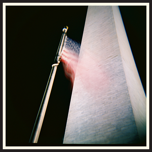 Film photo of an American flag blowing in the wind in front of the Washington Monument
