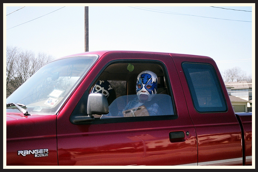 A luchador in a full face mask driving a car in Texas