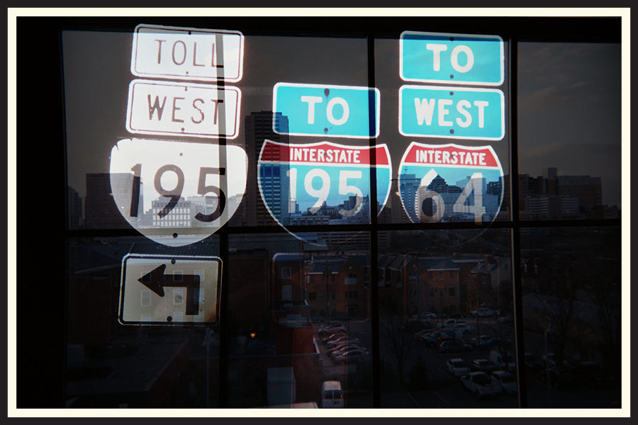 Film photo of a reflection of street signs in a window