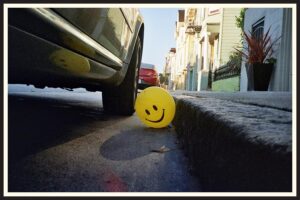 Film photo of a smiley face balloon in the street