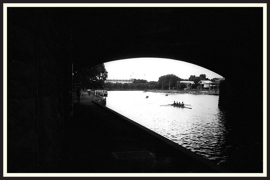 Black and white film photo of people rowing a boat in Melbourne.