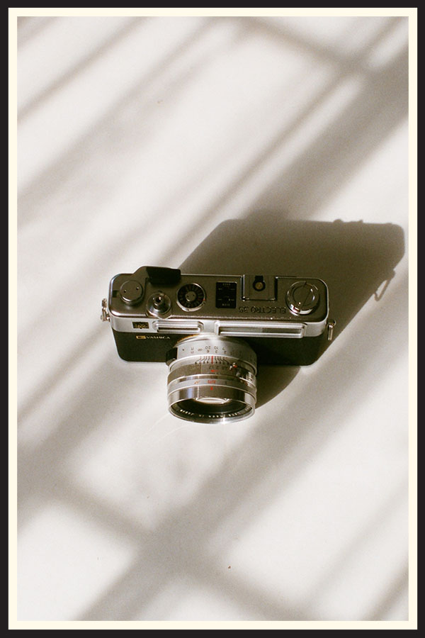 A rangefinder film camera on a white background.