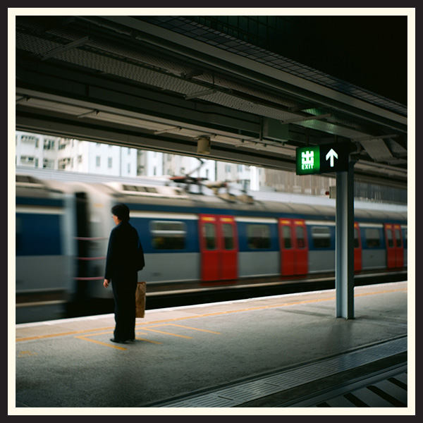 A passenger stands still as a train passes, showing motion blur.