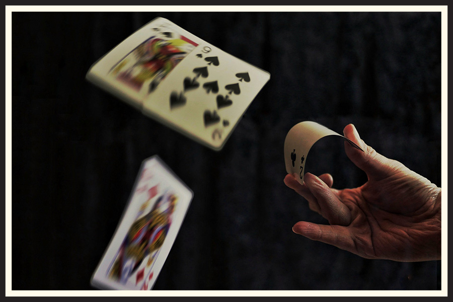 A hand shoots a deck of cards into the air, the cards showing motion blur because of the long shutter speed.