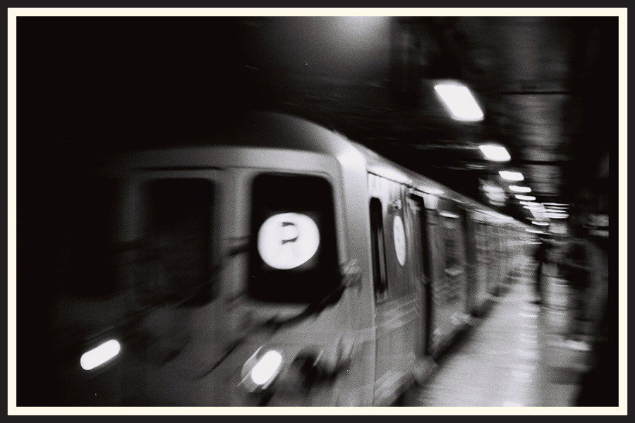 Black and white film photo of a train showing motion blur, taken with a slow shutter speed