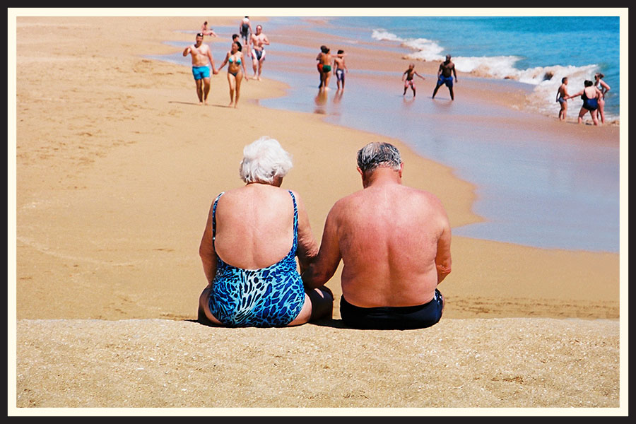 An older couple sitting together on the beach, taken on Kodak Ektar film.