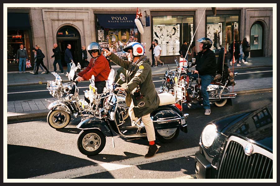 A group of men on mopeds on the street, taken on Kodak Ektar film.