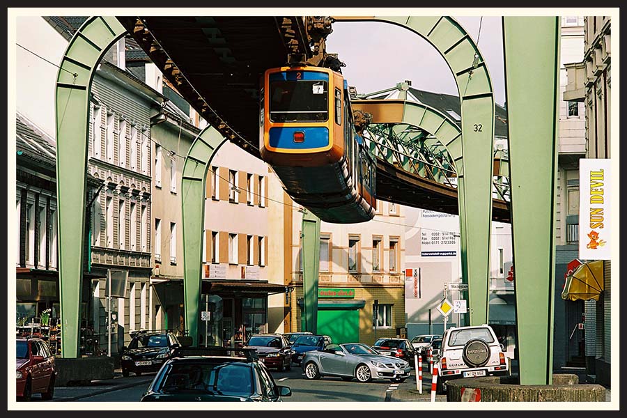 Suspended rail train riding over traffic in a film photo taken on Kodak Ektar 100.