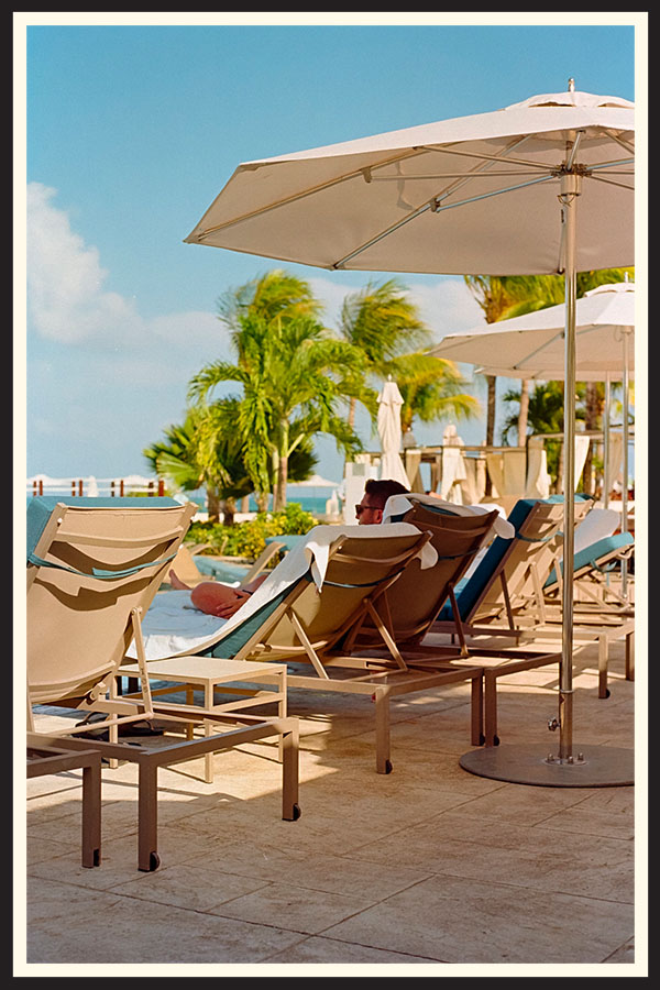 Film photo of a person lounging in a beach chair by the pool taken on Kodak Ektar 100 film.