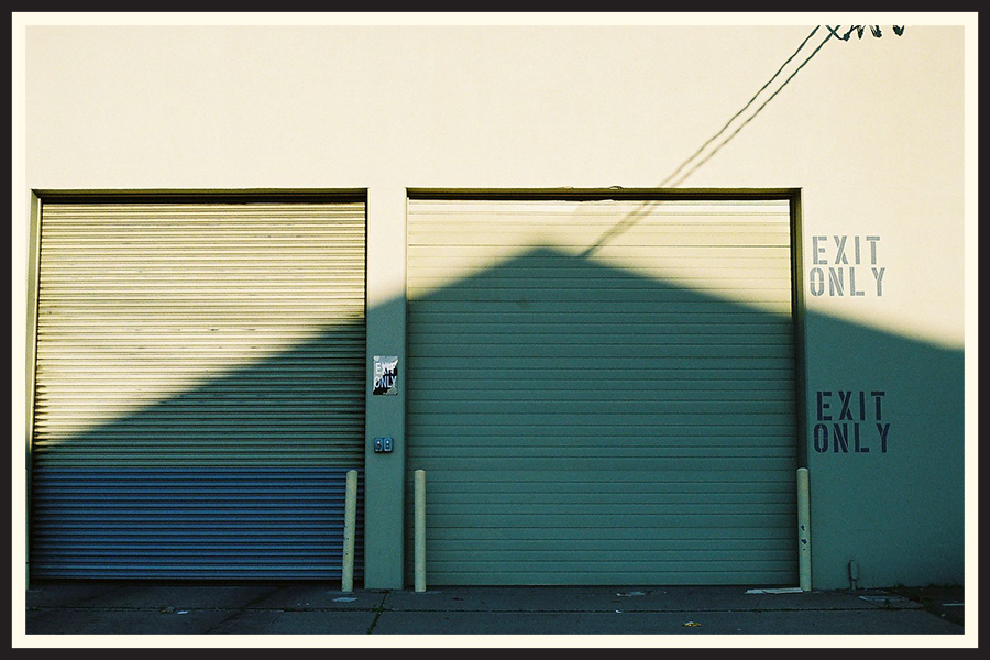 Film photo of a large garage door, showing the reflection of another building and power lines, taken on a Contax G2.