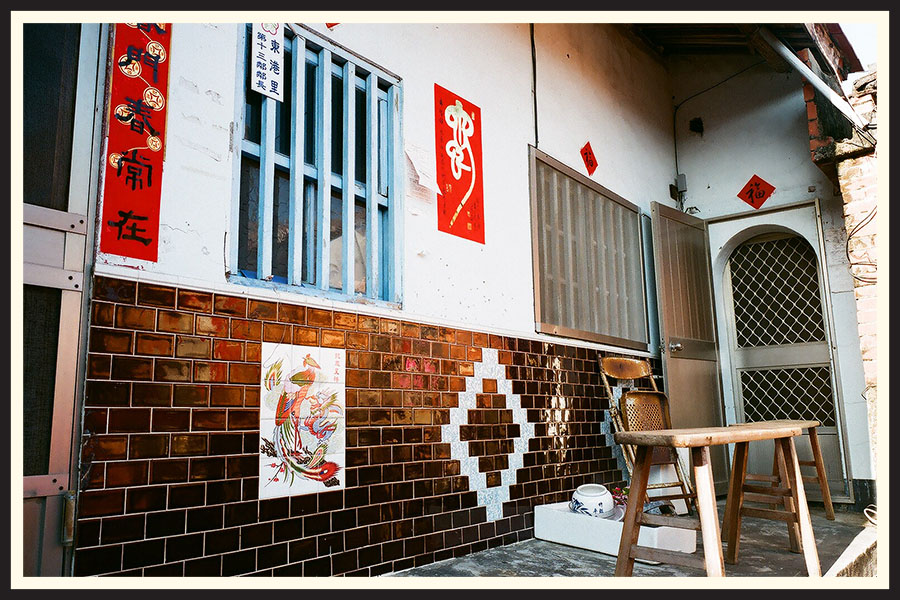 Sun soaked porch of a building with bright red accents on the walls, taken on a Contax G2 camera.