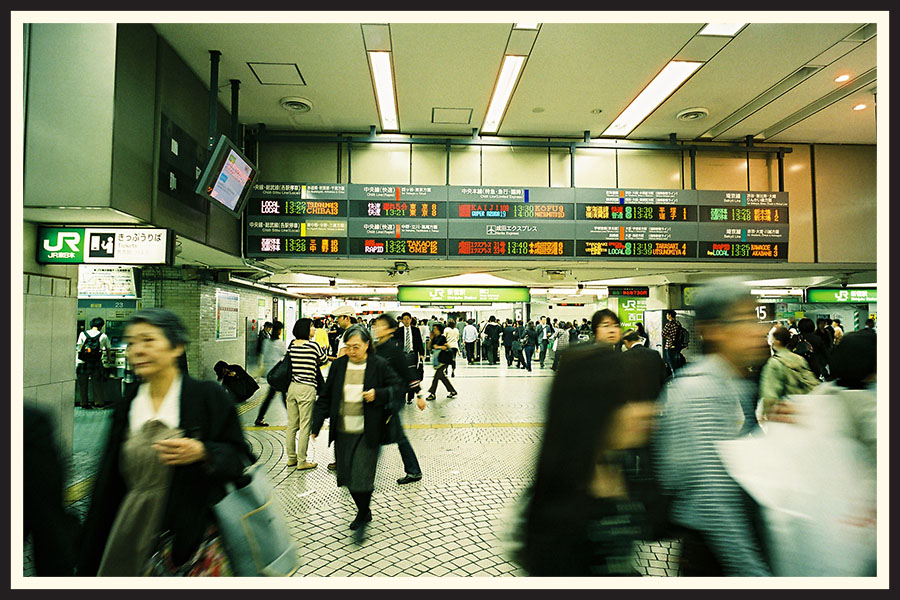 A bustling crowd of people walking through a train station, captured on a Contax G2 camera.