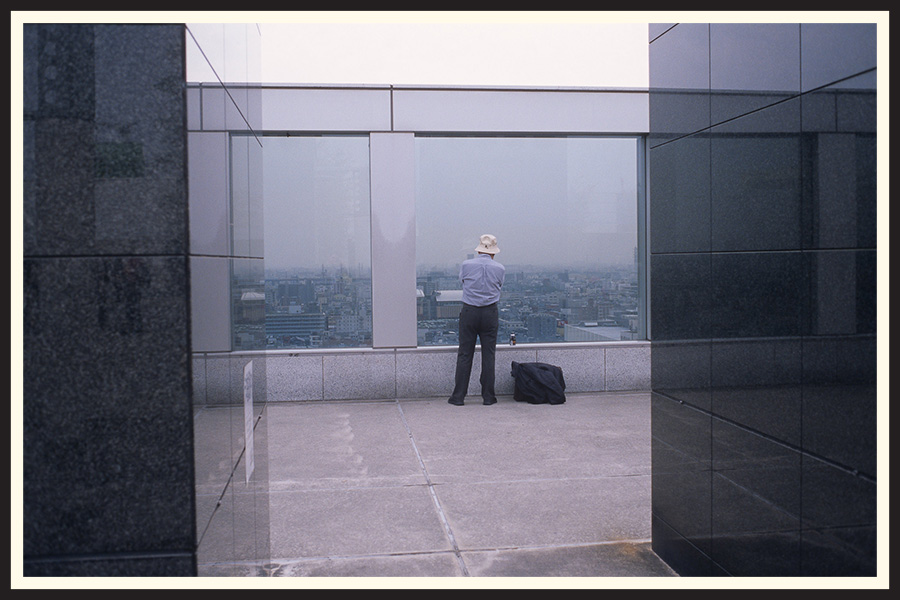 Photo of a man looking at the skyline from the top of a building, captured on a Contax G2 film camera.