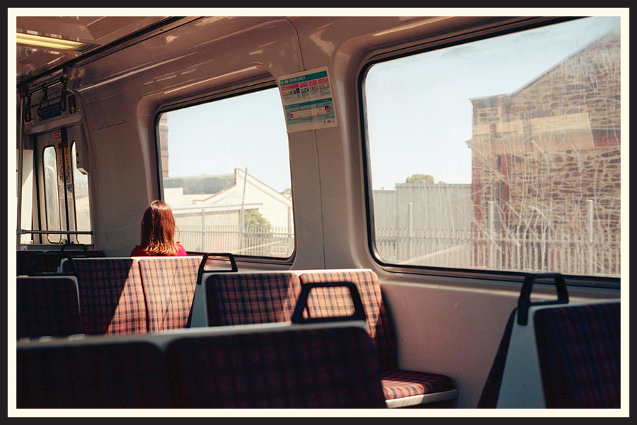 Film photo of a lone passenger sitting on a train, taken on a Contax G2.