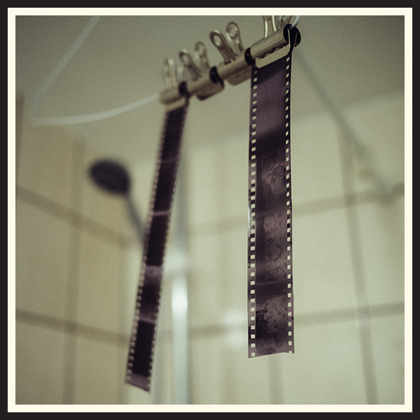 Film negatives hanging from a clip after being developed.