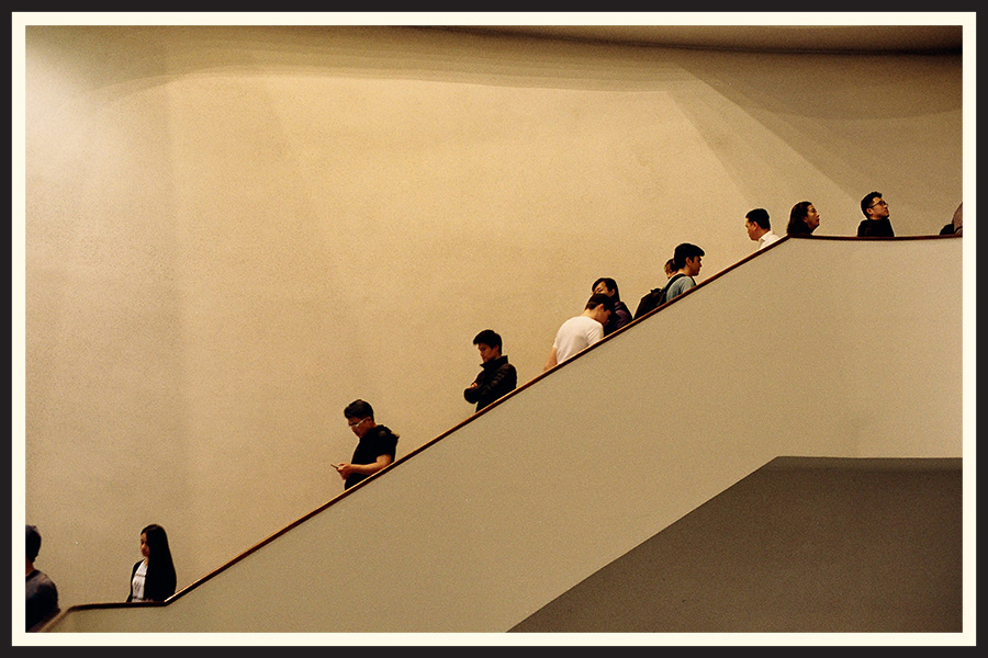 A line of people walking down a staircase, taken on Kodak Colorplus 200 film.