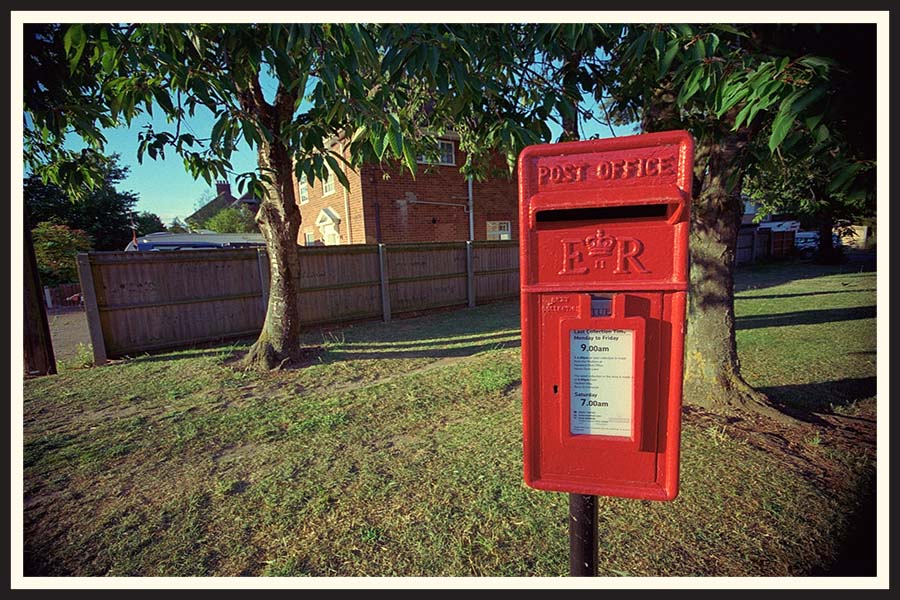 Bright red post office box with trees in the background, taken on Kodak Colorplus 200.