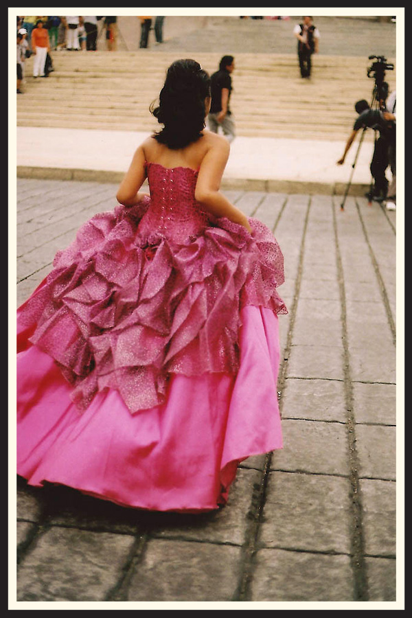 Woman in a bright pink dress running away from the camera, taken on Kodak Colorplus 200 film.