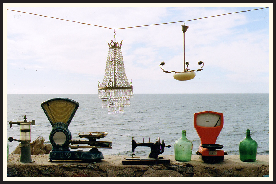 A collection of antique fixtures sitting on a ledge in front of the ocean, taken on Portra 800 color film.